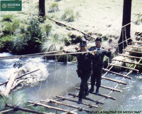 Imagen de El director de la Escuela Médico Militar, el general Enrique Espino, y un militar no identificado atraviesan un puente de troncos, como parte de los ejercicios de maniobras militares (atribuido)