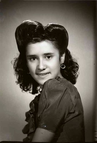 Imagen de Retrato de jovencita sonriendo con peinado estilizado, arracadas y vestido formal en estudio (atribuido)