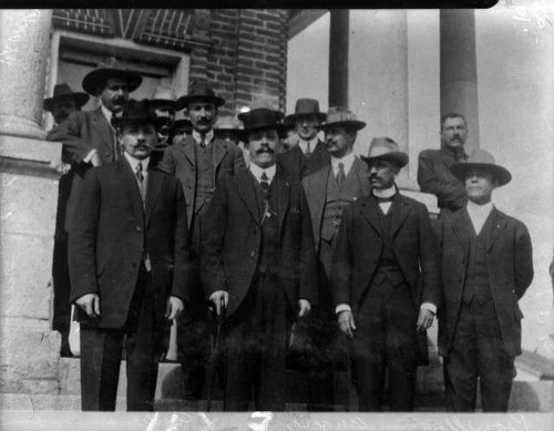 Imagen de Felipe Ángeles y otros revolucionarios fuera de un edifico, retrato de grupo