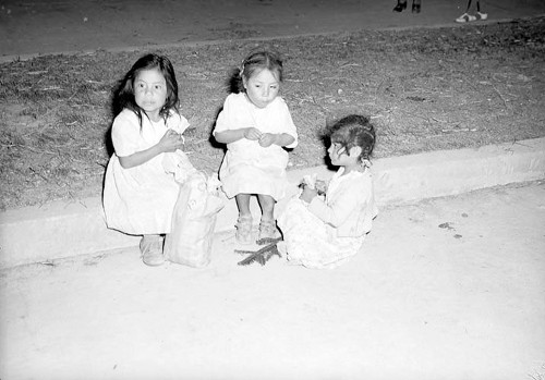 Imagen de Niñas sentadas a la orilla de una calle, comiendo dulces (propio)
