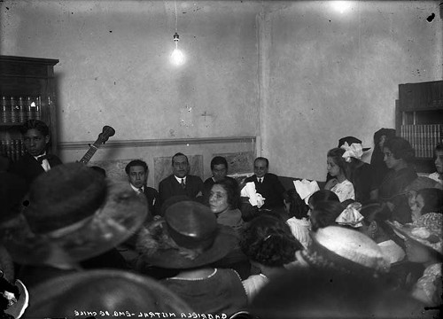 Imagen de Gabriela Mistral, embajadora de Chile acompañada de otros diplomáticos durante un evento social en un salón (propio)