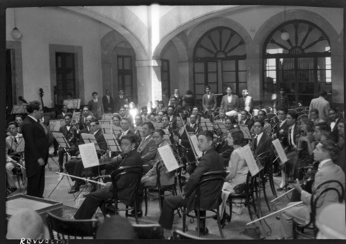 Imagen de Silvestre Revueltas ante una orquesta, en el patio central de un edificio (propio)