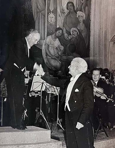 Imagen de Manuel M. Ponce saludando al maestro Rocabruna con orquesta de fondo. (atribuido)