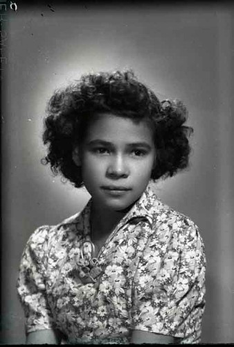 Imagen de Retrato de niña con vestido estampado, peinado estilizado y broche en el pecho en estudio (atribuido)