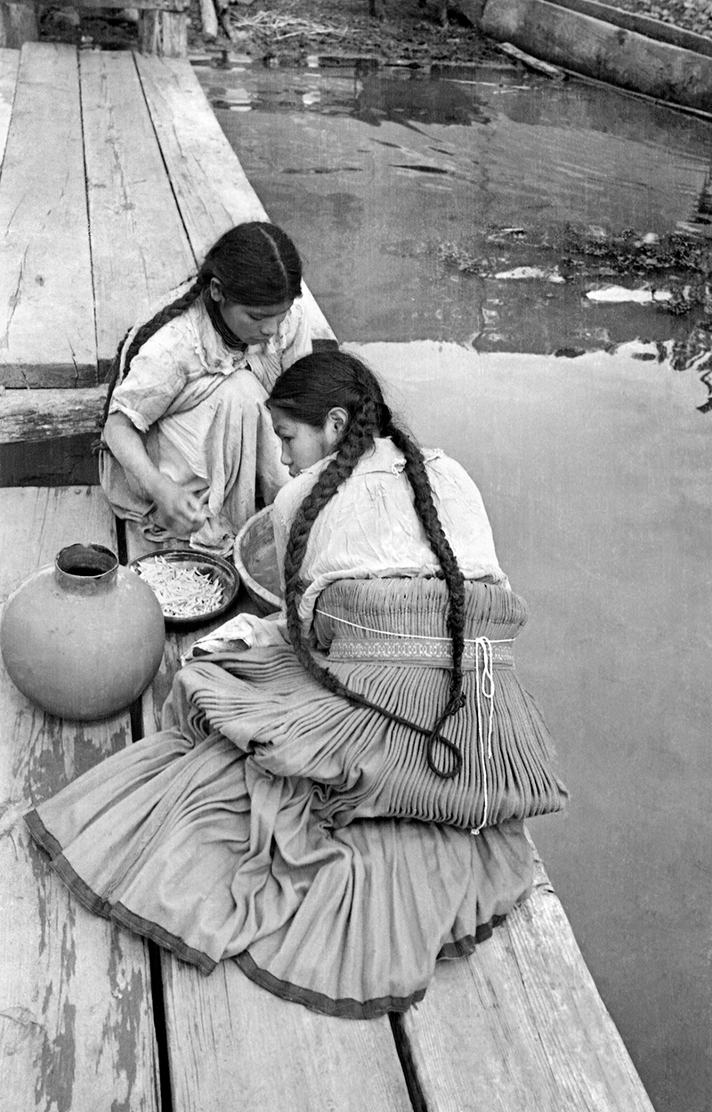 Retrato de dos mujeres junto al lago lavando maíz.